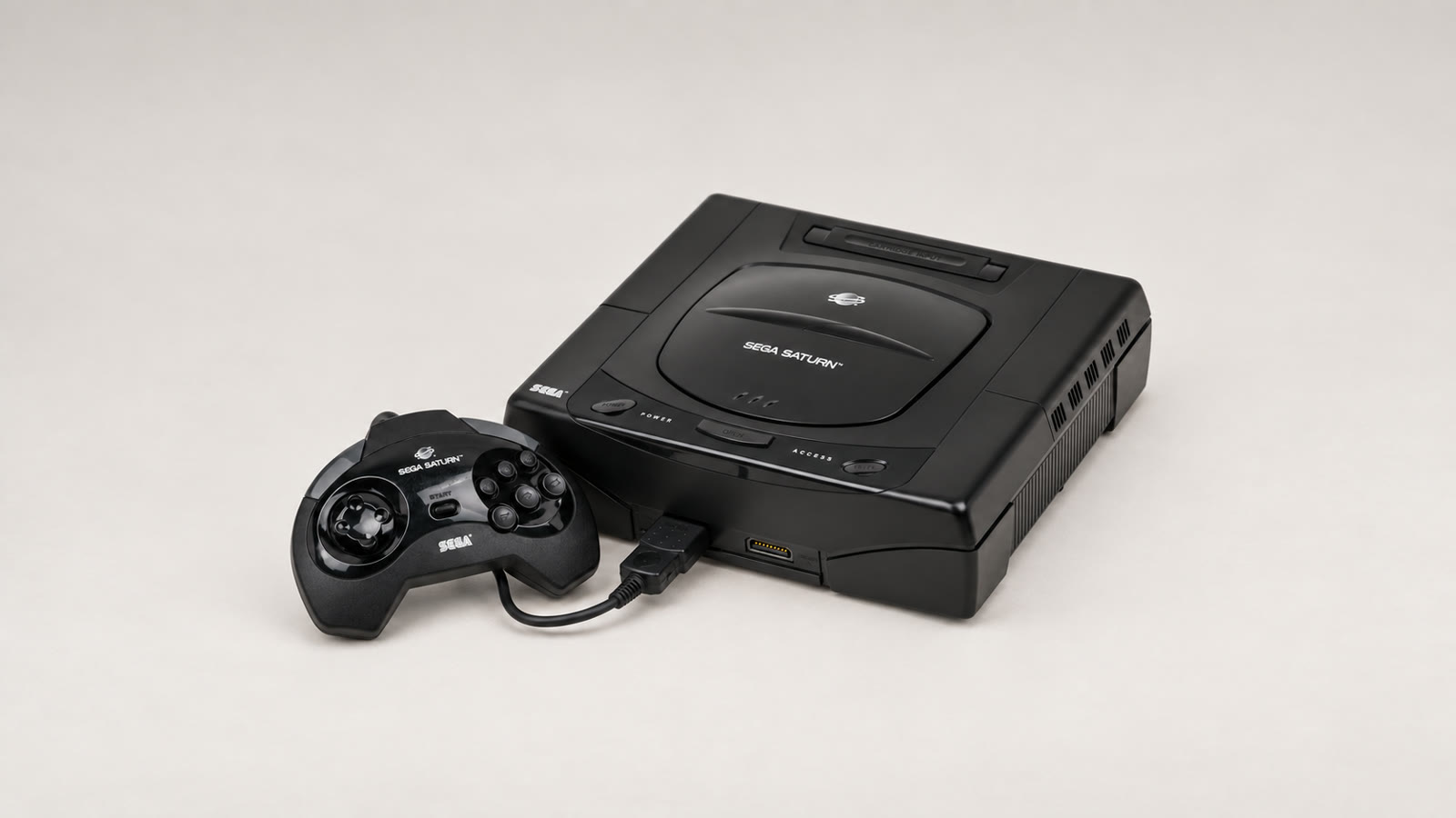 Schwarzer Sega Saturn der ersten US-Modellreihe mit kabelgebundenem Controller auf hellem Hintergrund