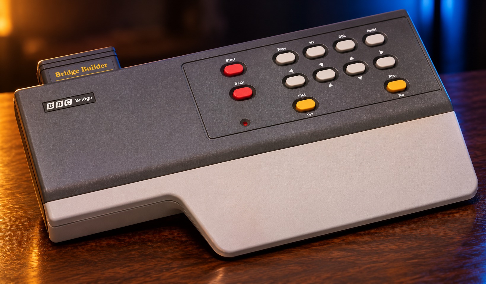BBC Bridge Companion mit passendem Controller auf einem dunklen Holztisch vor dezent beleuchtetem Hintergrund