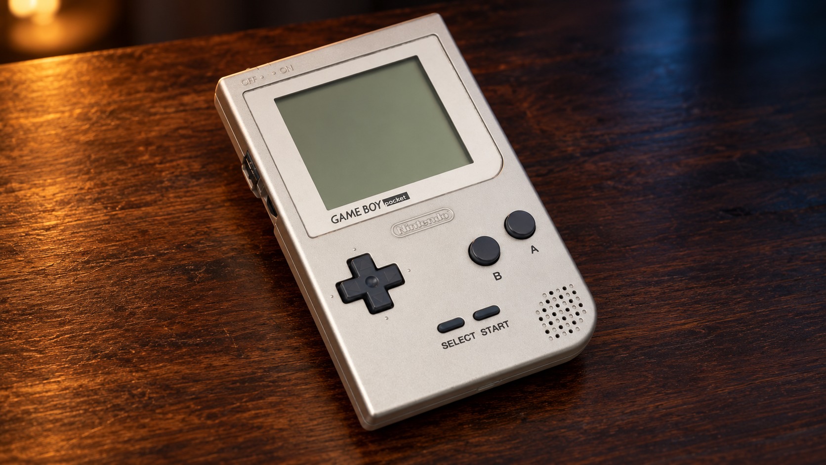 Nintendo Game Boy Pocket mit integrierter Steuerung auf einem dunklen Holztisch vor dezent beleuchtetem Hintergrund
