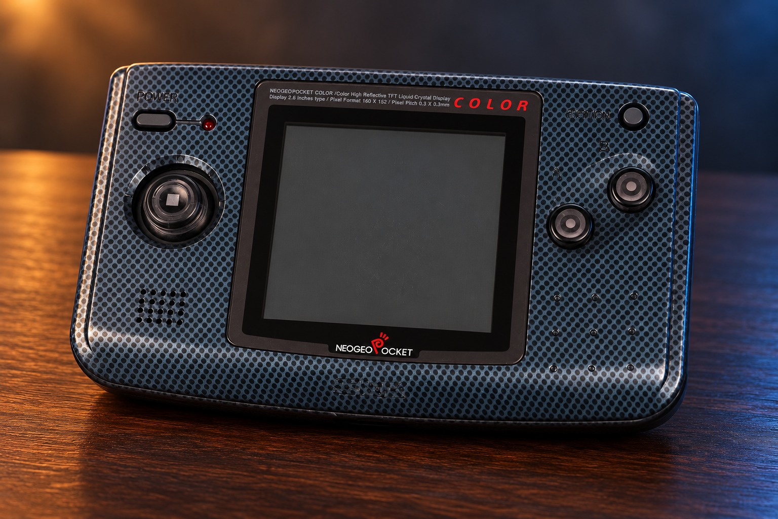 SNK Neo Geo Pocket Color mit integrierter Steuerung auf einem dunklen Holztisch vor dezent beleuchtetem Hintergrund